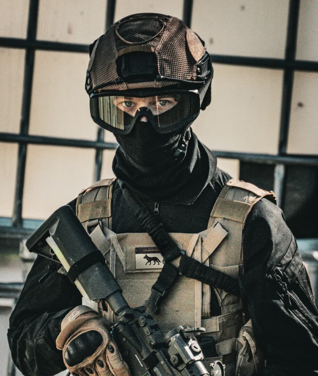 Coyote Syndicate operator in a black helmet, goggles, and tan chest rig
